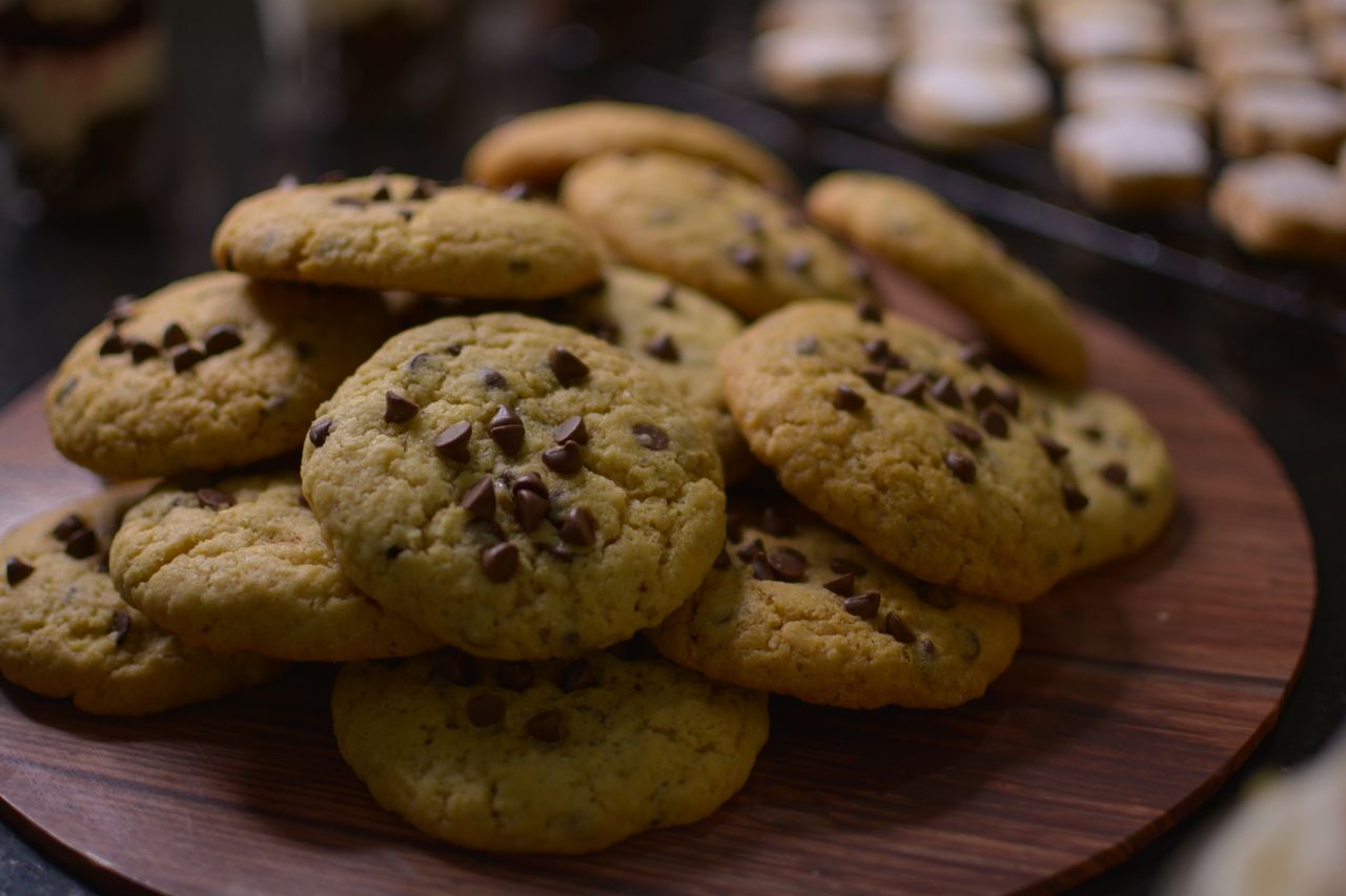Close-up view of freshly baked chocolate chip cookies on a wooden tray.